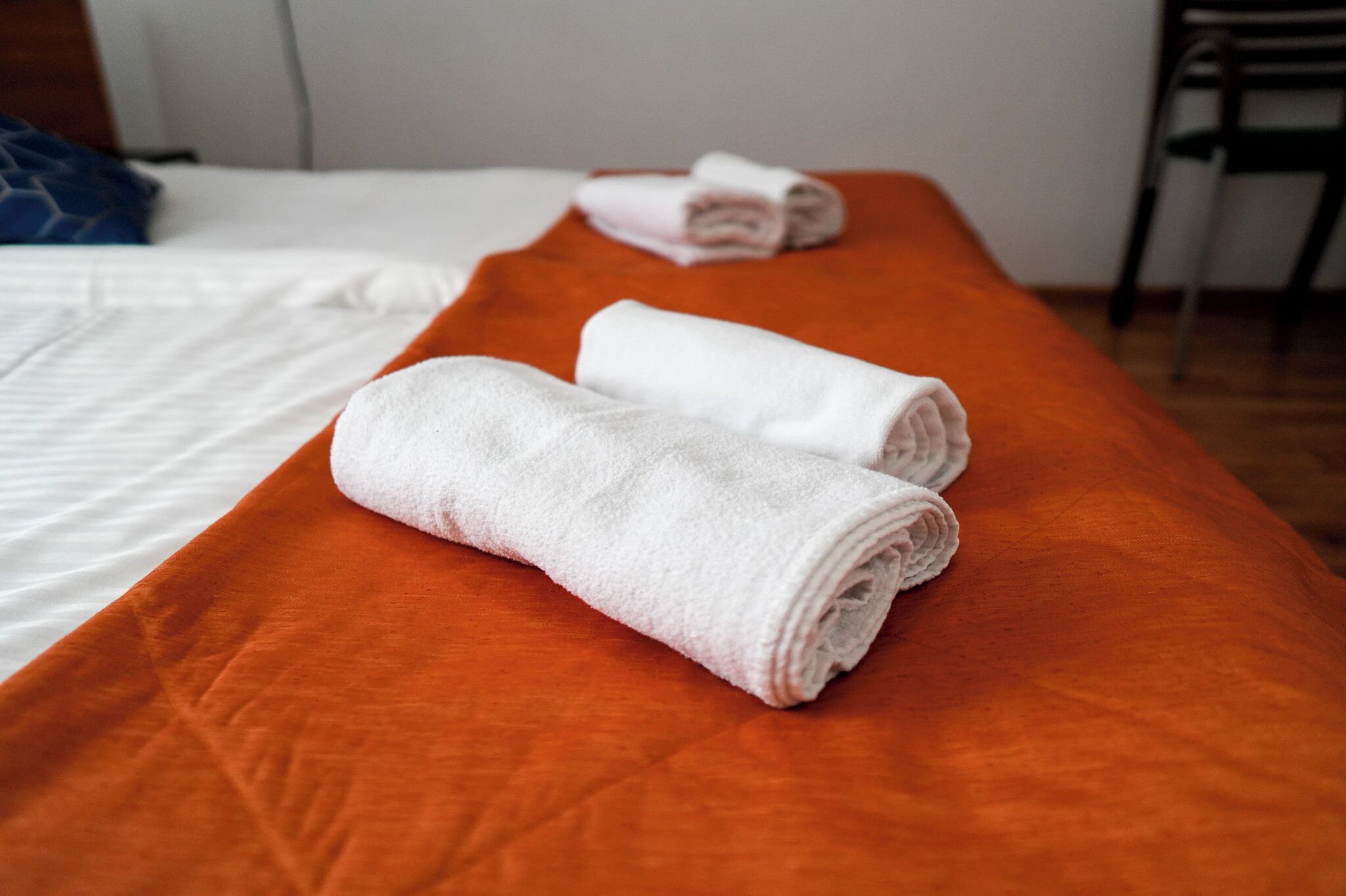 Un lit avec une couvre-lit orange et deux serviettes blanches roulées.