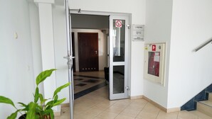 An interior hallway with a potted plant, a door leading to another room, and a fire extinguisher mounted on the wall. - Hotel Sutoris (Bochnia)