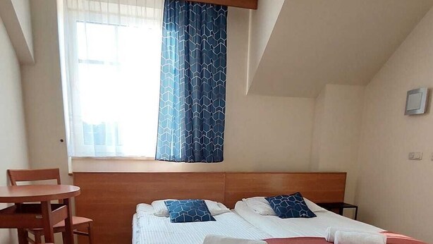 A bedroom with a bed, a desk, and a chair. - Hotel Sutoris (Bochnia)