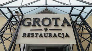 A sign for 'GROTA RESTAURACJA' with a camera above it, mounted on a metal structure. - Hotel Sutoris (Bochnia)