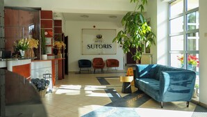 Een hotel lobby met een receptiebalie, een zithoek en een groot raam.