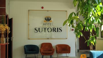 En hotellreception med en skylt som visar texten ”HOTEL SUTORIS” och två stolar framför.