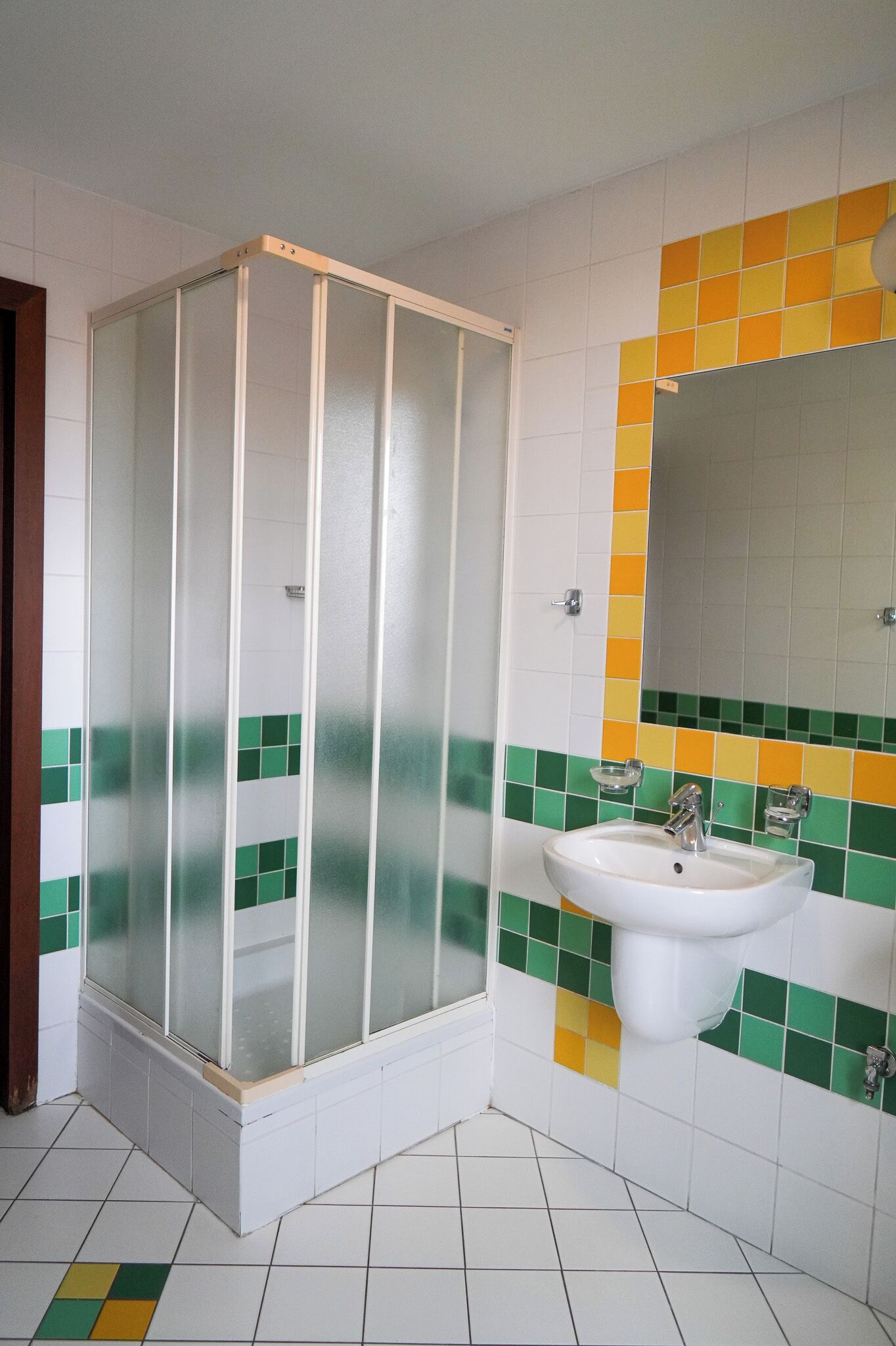 A bathroom with a shower enclosure, a sink, and a mirror.