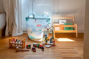 A room with a wooden floor, a white door, a wooden shelf with boxes, a colorful bag, and wooden toys. - Your ideal urban retreat in Barcelona. This apartment combines functional design with an unbeatable location next to Ciutadella Park and the 22@ district. Featuring two full bathrooms and high-speed Wi-Fi, it offers everything you need for a comfortable  (Barcelona)