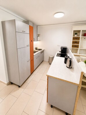 A modern kitchen with a central island, built-in appliances, and a white tiled floor.