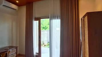 A room with a wooden ceiling, a large window with curtains, a flat-screen TV, and a tiled floor.
