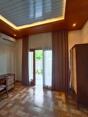 Una habitación con techo de madera, un ventanal con cortinas, un televisor de pantalla plana y suelo de baldosas.