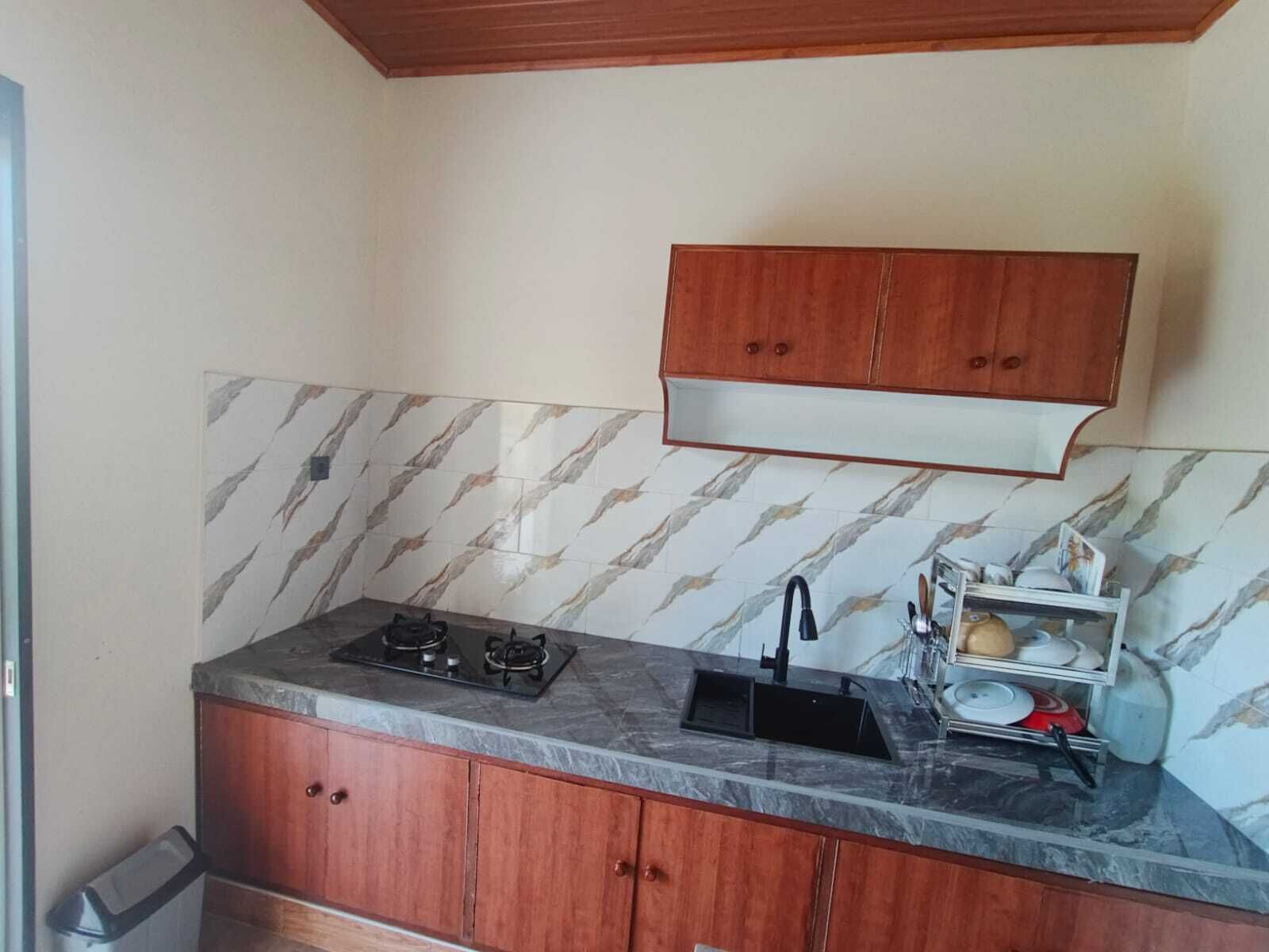 A compact kitchen with a gas stove, a sink, and a wooden cabinet above the countertop.