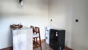 Une cuisine avec un plan de travail en marbre, une chaise en bois, un réfrigérateur noir et un ventilateur de plafond.