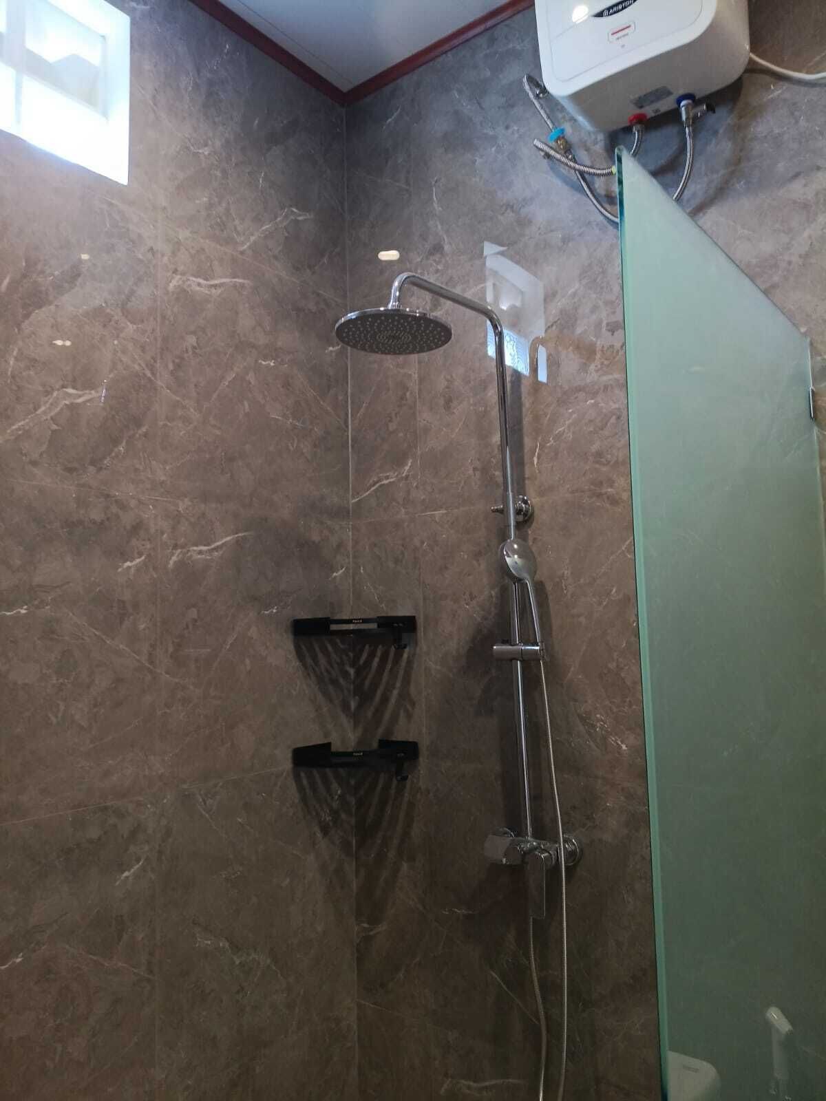 A shower with a handheld showerhead, a glass-enclosed shower stall, and a wall-mounted control panel.