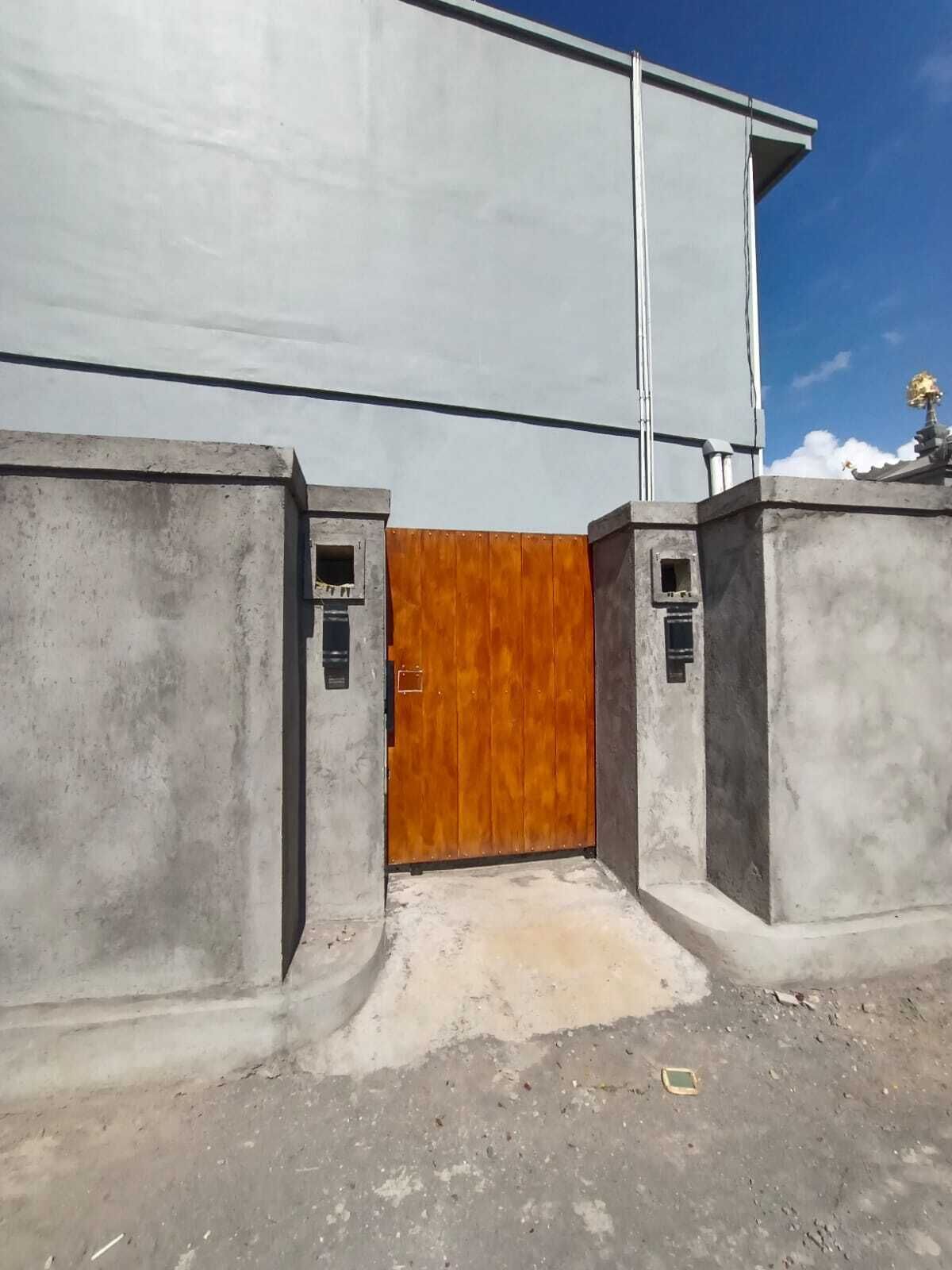 A concrete building with a wooden door, two small windows, and a clear sky.