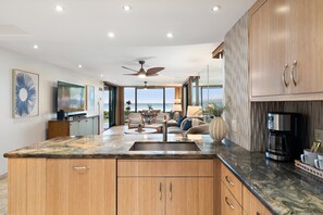 Una cocina moderna con una isla grande, armarios de madera y vistas al exterior.