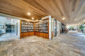 A spacious lobby with a herringbone-patterned floor, wooden panel bookshelves, and a ceiling with wooden beams. - Oceanfront Retreat with Panoramic Views & Beachfront Lanai -Mahana (Lahaina)