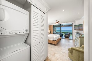 A compact laundry area featuring an in-unit stacked washer and dryer tucked neatly behind clean white louvered doors. - Oceanfront Retreat with Panoramic Views & Beachfront Lanai -Mahana 109 (Lahaina)