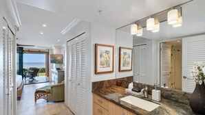 Un baño moderno con un espejo grande, encimera de mármol y armarios de madera.