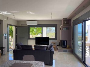 Ein modernes Wohnzimmer mit Flachbildfernseher, einer Couch, einem Esstisch und einem Kamin.