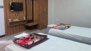 Una camera d'albergo con un letto, un armadio, una ventola a soffitto e un condizionatore.