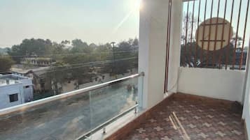 A balcony with patterned flooring, a glass railing, and a view of a street and buildings.