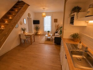 A modern kitchen with a built-in sink, wooden flooring, and a staircase. - Bohemian & Nature Retreat (Nuaillé-d'Aunis)