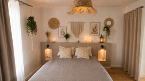 Une chambre à coucher avec un grand lit, deux lampes fixées au mur et des éléments décoratifs suspendus au mur.