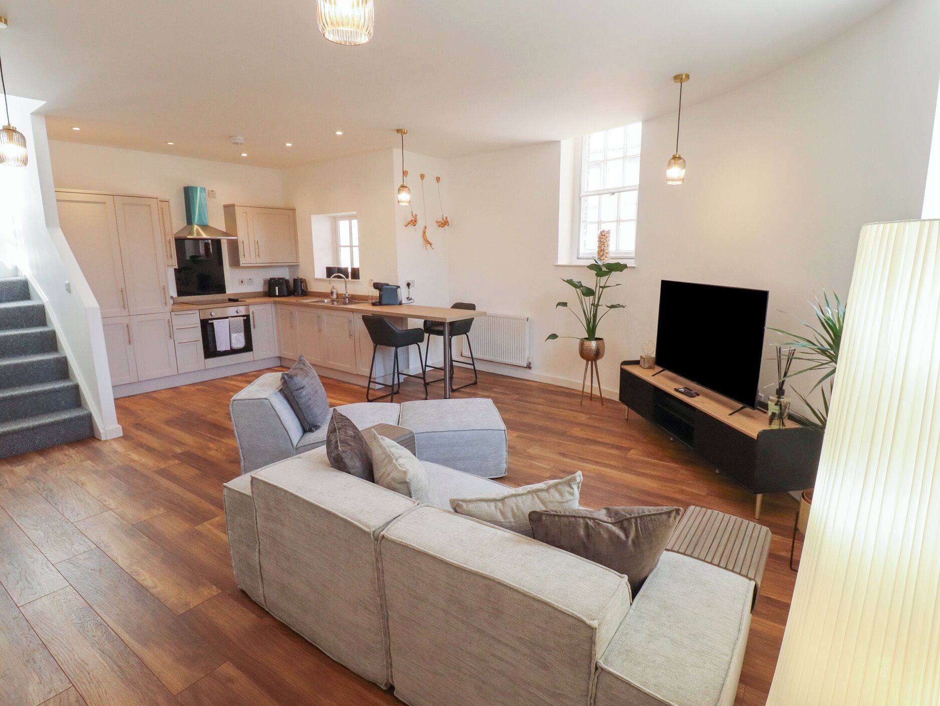 A modern living space with a sofa set, a dining area, a kitchen, and a TV.