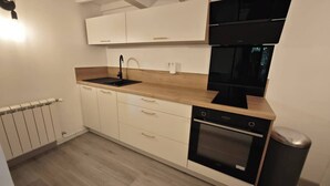 A modern kitchen with white cabinets, a black sink, and a built-in oven. - One-bedroom apartment with a pool, in a Provençal farmhouse (Cavaillon)