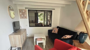 A modern living room with a red sofa, a black sofa, a white side table, a wooden cabinet, and a large window. - One-bedroom apartment with a pool, in a Provençal farmhouse (Cavaillon)