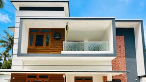 A modern two-story building with a flat roof, a balcony, and a checkered floor pattern.