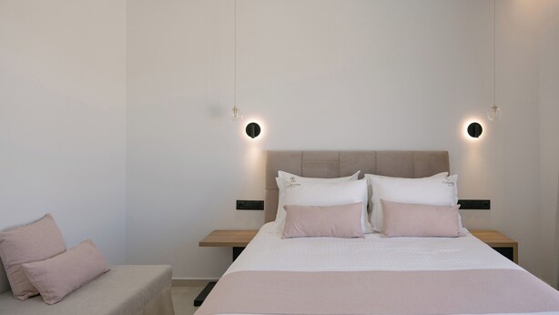 Een moderne hotelkamer met een groot bed, twee nachtkastjes, een klein zithoekje en een nachtkastje.