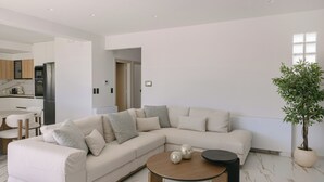 Een moderne woonkamer met een hoekbank, een salontafel en een potplant.