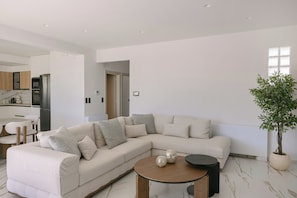 A modern living room with a sectional sofa, a coffee table, and a potted plant. - Norma Villa, Heated Pool, Walk to Shops & Dining (Rethymno)