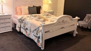 Ein Schlafzimmer mit einem weißen Bett, zwei Nachttischen mit Lampen, einer dunklen Wand und einer Deckenleuchte.