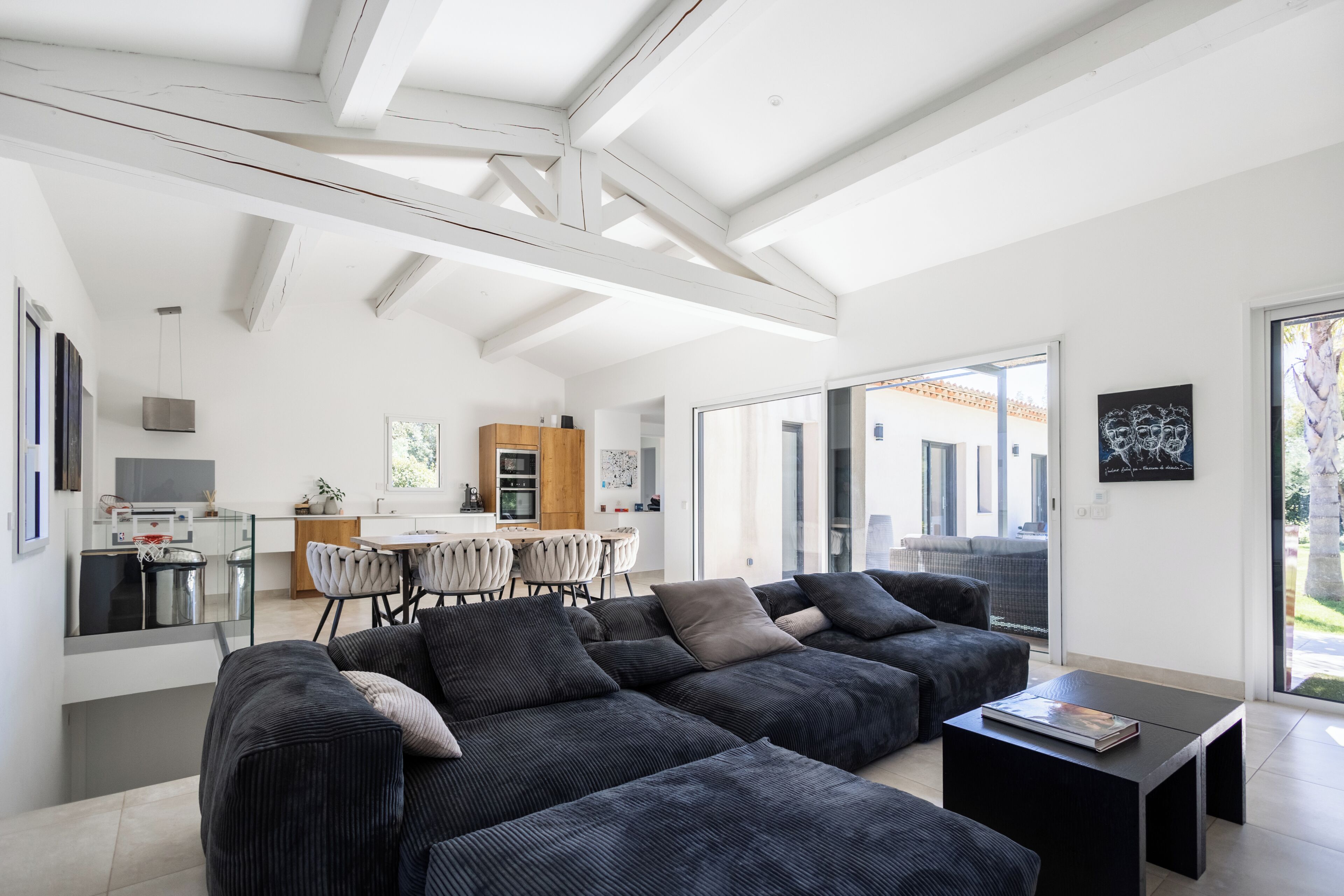 A modern living room with a sectional sofa, a dining area, and a kitchen.