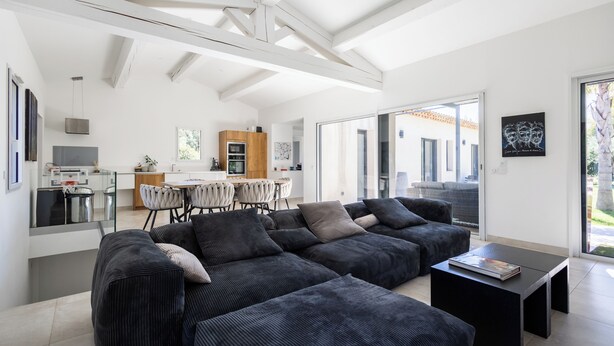 Een moderne woonkamer met een modulaire bank, een eethoek en een keuken.