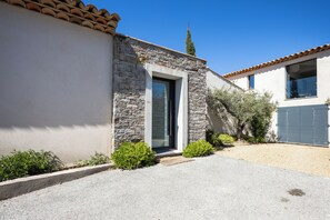 A modern house with a stone facade, a door, and a small garden area. - Villa L'Aparté Beauvallon | Pool, Movie Theater, Fitness Center & Golf (GRIMAUD)