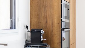 Een moderne keuken met een ingebouwde oven, een koffieapparaat en een raam.