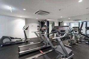 A gym with various exercise equipment including treadmills and elliptical machines. - Luxury CBD Top Floor Apt w/Gym spa pool n Car Spot (Southbank)