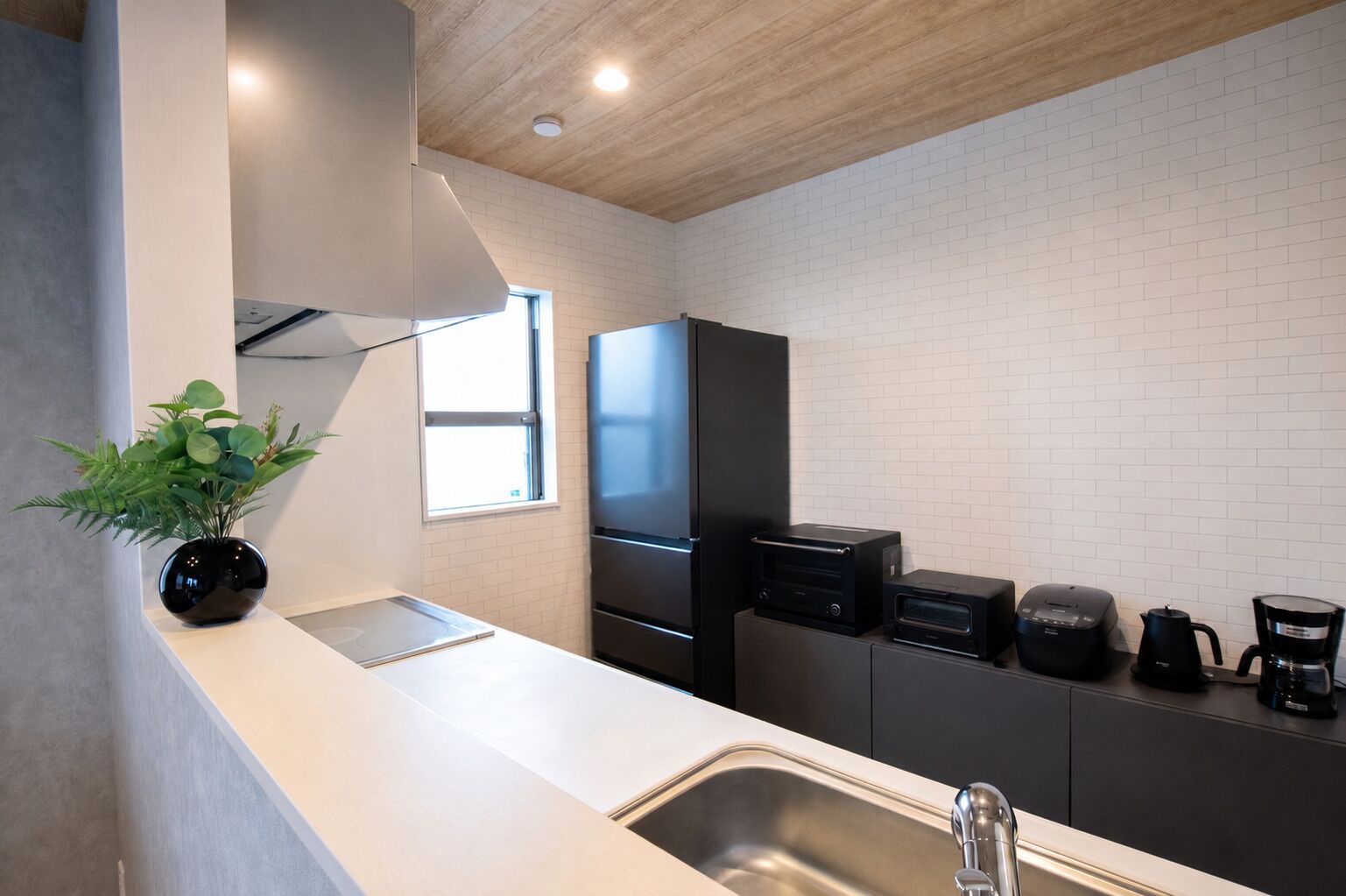 A modern kitchen with a white countertop, stainless steel sink, and black appliances.