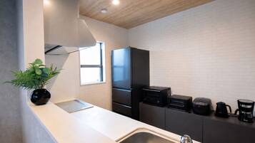 A modern kitchen with a white countertop, stainless steel sink, and black appliances.