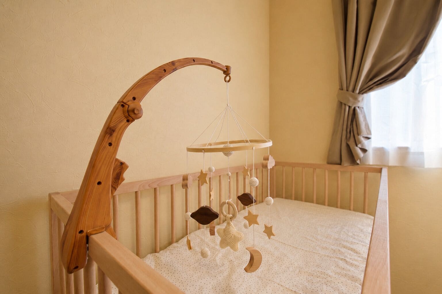 A wooden crib with a hanging mobile.