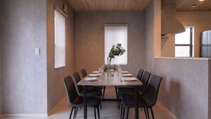 A modern dining area with a rectangular table, black chairs, and a vase with green plants. - Fuji Terrace -EIRAN- (Gotemba)