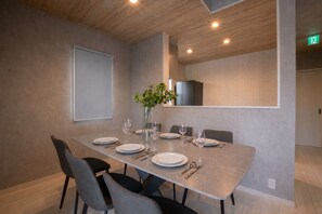 Un comedor moderno con una larga mesa dispuesta para cuatro personas, rodeada de sillas.