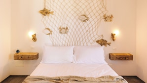 A bedroom with a bed, two nightstands, a wall hanging with a net and decorative elements, and wall-mounted lights. - Appartamento Sea - Tenuta Fascianello (Puglia)