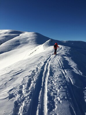 Ein verschneiter Bergpfad mit einer Person in roter Kleidung.