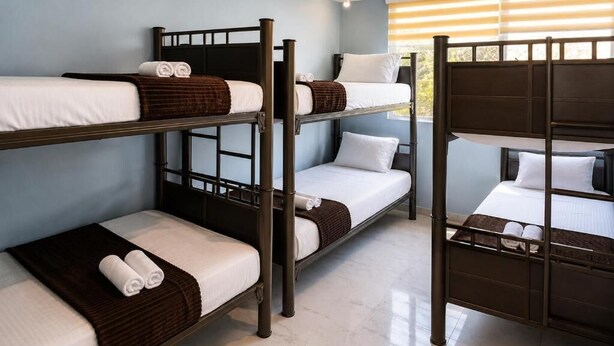 A bunk bed room with three levels, each with a mattress and pillows, in a room with a tiled floor and a window with blinds. - Hotel Boutique Venecia CDMX (Mexico City)