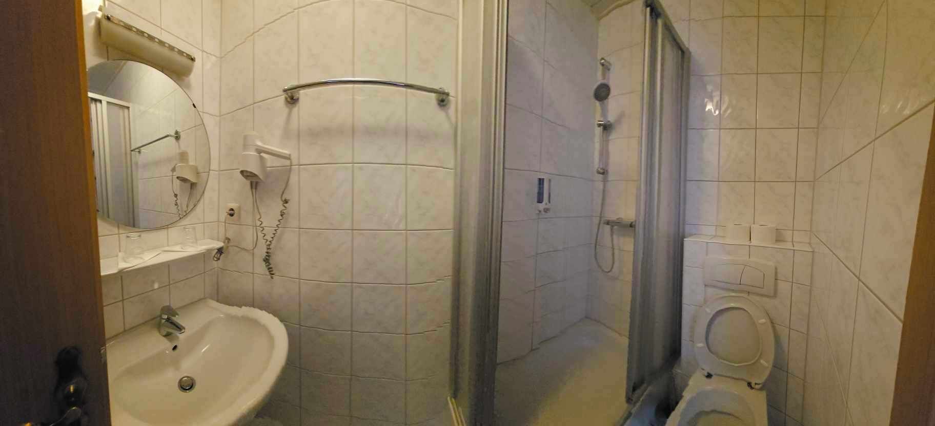 Ein Badezimmer mit Waschbecken, Spiegel, Dusche und Toilette.