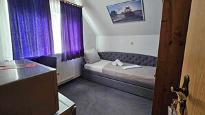 A room with a bed, a desk, and a window with curtains.