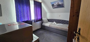 A room with a bed, a desk, and a window with curtains.