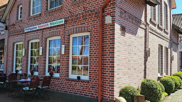 A brick building with a sign indicating it offers Filipino, Spanish, and Mexican cuisine.