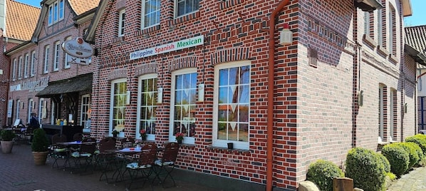 A brick building with a sign indicating it offers Filipino, Spanish, and Mexican cuisine.